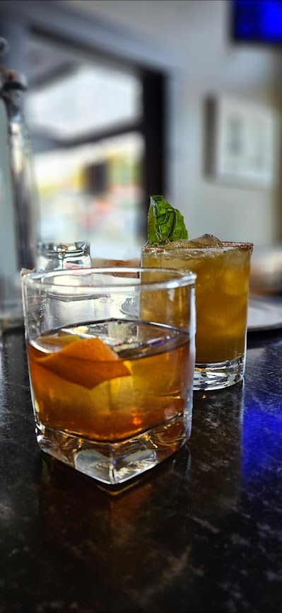 Two craft cocktails on the Big Mill bar: an old fashioned with orange peel and a garnished tiki drink.