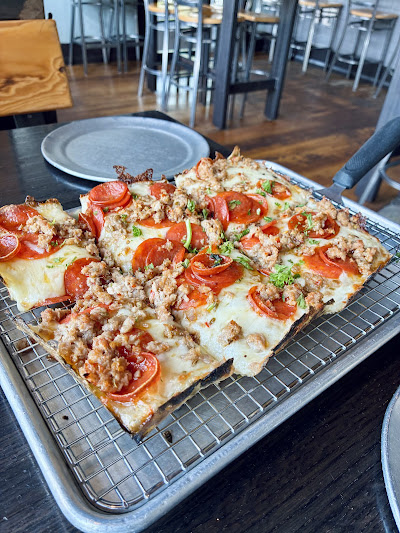 Detroit-style pizza topped with pepperoni and sausage on a wire rack.